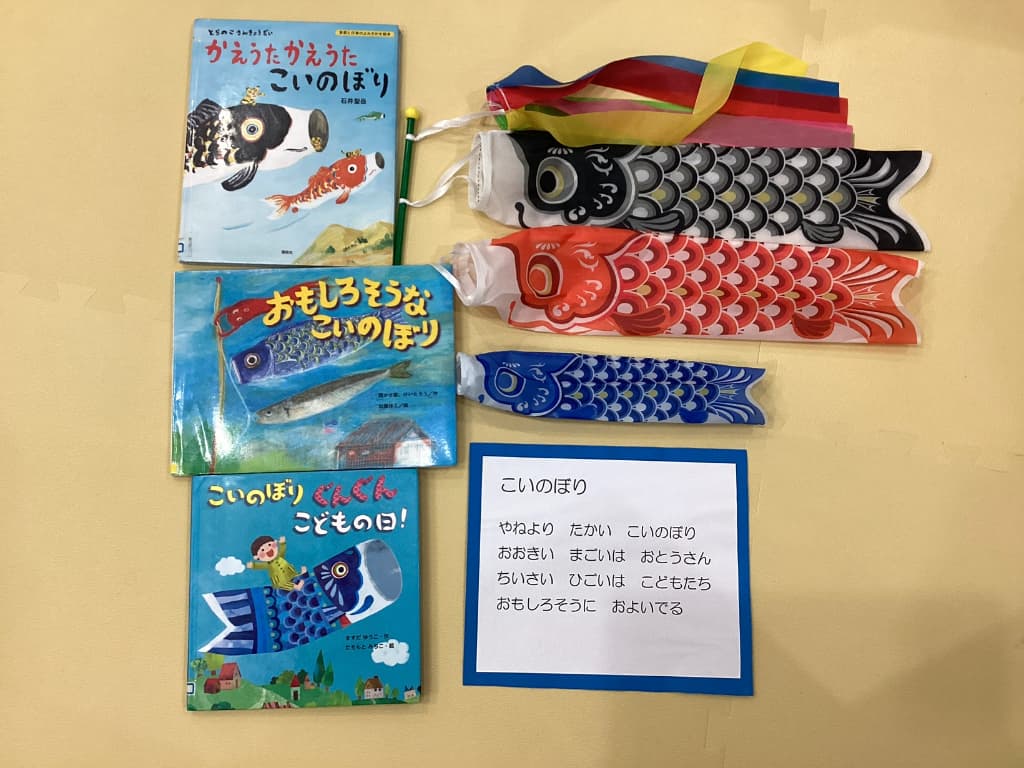こいのぼりがテーマの絵本が3冊と、高のぼり飾り、同様こいのぼりの歌詞が書いた壁面飾りが並べられている。
