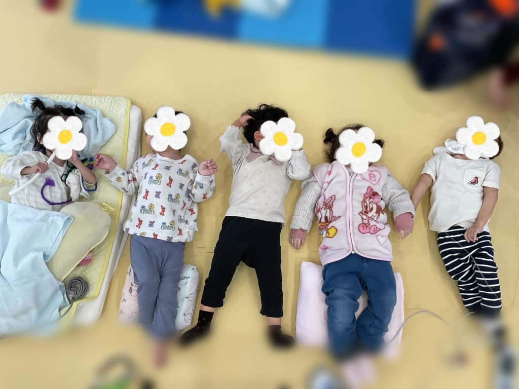 保育室で5人の子どもたちが並んで横になって過ごしている様子