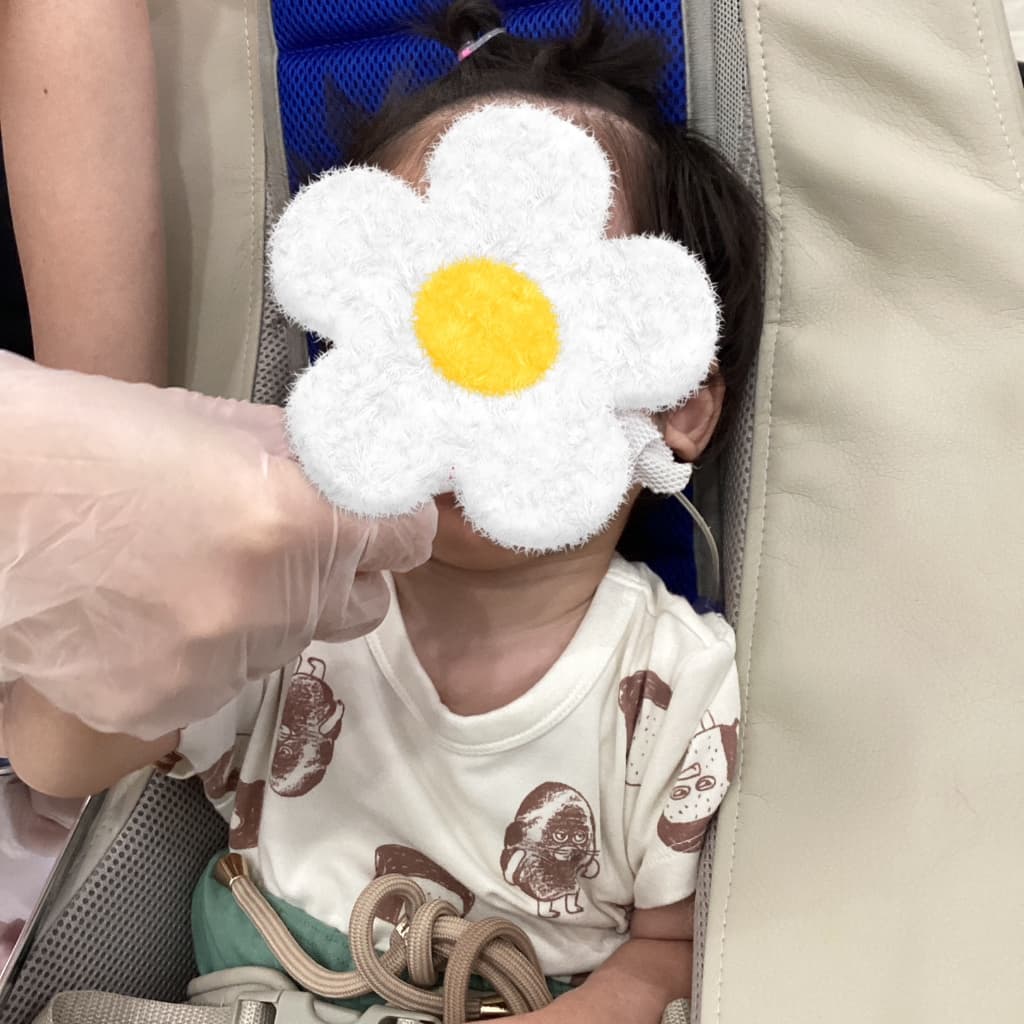 クッションチェアに座った子どもに対し、支援者が口元のケアを行っている様子