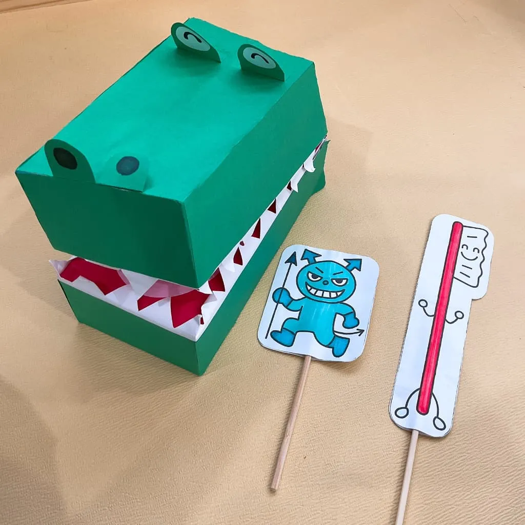 子どもの歯磨き指導に使うグッズ。紙で作ったワニの顔の模型とばい菌・歯ブラシのいらすとが並んでいる
