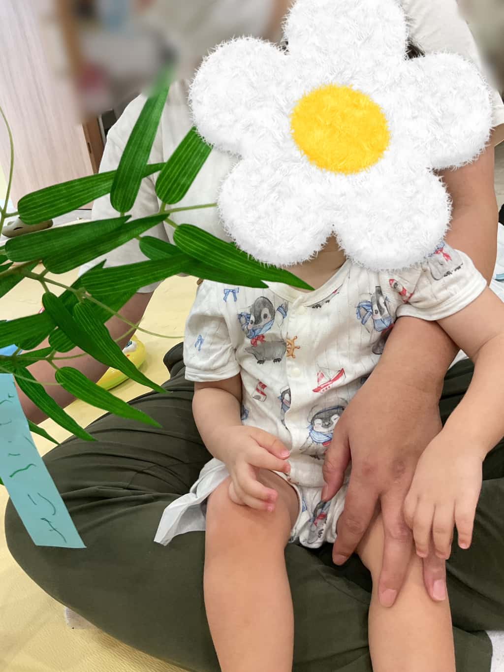 支援者に抱っこされた子どもが笹に短冊を飾ろうとしている様子